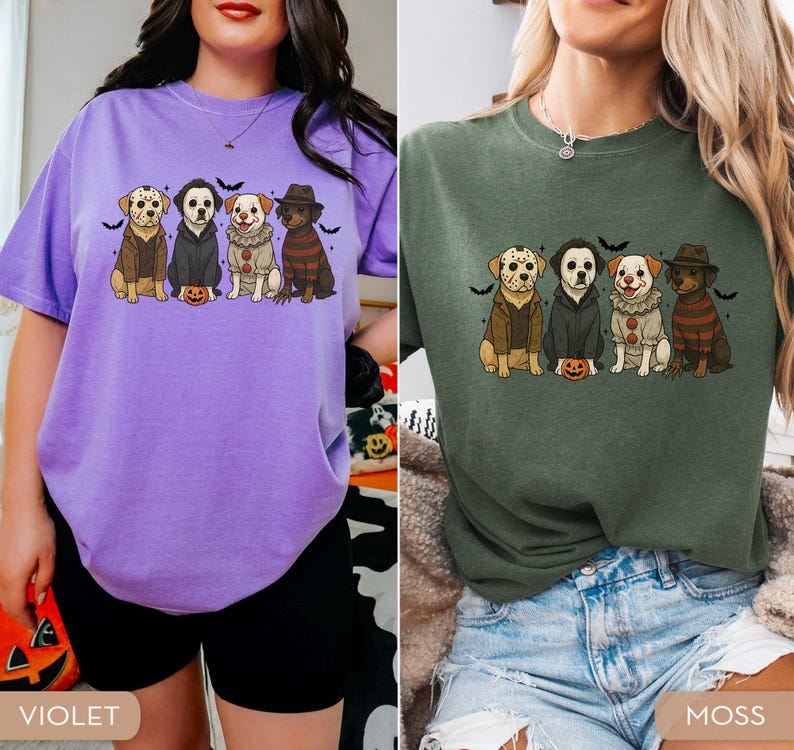 May include: Two t-shirts, one violet and one moss green, each featuring a graphic of four dogs dressed as horror movie characters. The dogs are wearing costumes and are sitting in a row with bats above them.
