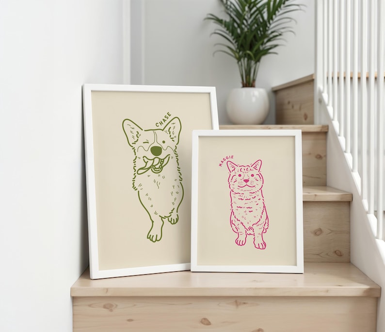 May include: Two framed art prints featuring pet illustrations. One print shows a green outline of a dog with the name "Chase" above it. The other print shows a pink outline of a cat with the name "Maggie" above it. Both prints have a cream-colored background and white frames.