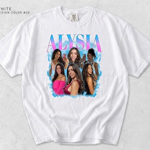 K&ouml;nnte beinhalten: Wei&szlig;es T-Shirt mit einem Grafikdesign mit dem Namen "ALYSIA" in einem Farbverlauf aus Rosa und Blau. Das Design enth&auml;lt Bilder von mehreren Frauen. Das Shirt hat einen Rundhalsausschnitt und kurze &Auml;rmel.