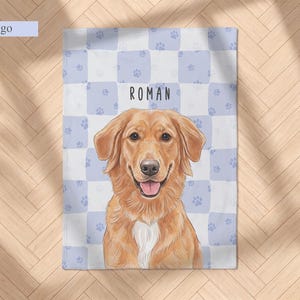May include: A rectangular blanket featuring a light blue and white checkered pattern with small paw prints. Centered is a golden-colored dog illustration with a white chest patch and an open mouth. The name ROMAN is printed above the dog.