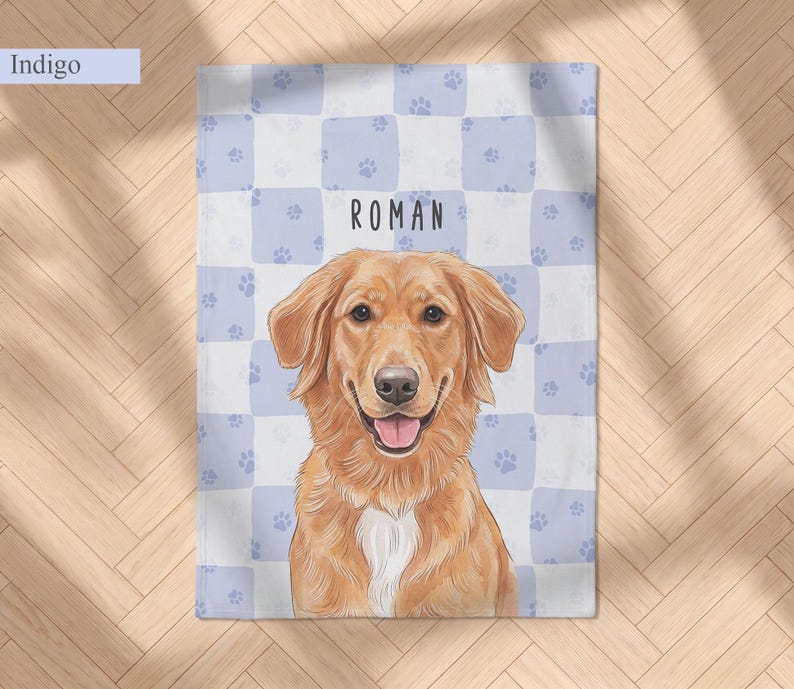 May include: A rectangular blanket featuring a light blue and white checkered pattern with small paw prints. Centered is a golden-colored dog illustration with a white chest patch and an open mouth. The name ROMAN is printed above the dog.