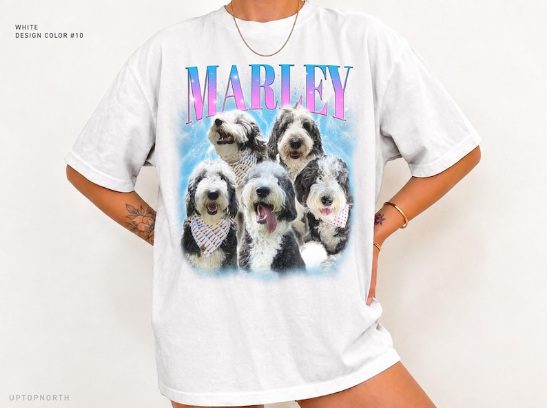 May include: A white short-sleeve t-shirt featuring a graphic print of five black and white dogs with bandanas. The text MARLEY is printed in a blue and pink gradient font above the dogs, set against a light blue cloudy background.