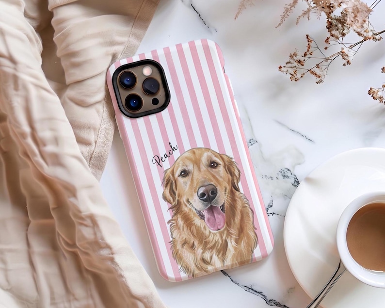 May include: A smartphone case featuring a vertical pink and white striped pattern. The case displays a detailed illustration of a golden retriever dog with its tongue out, and the name Peach is written in black cursive script above the dog.