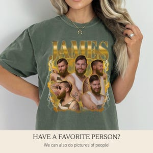 May include: A sage green short-sleeve t-shirt featuring a graphic print with the name JAMES in gold lettering at the top. Below the text are five different photographic portraits of the same bearded individual, surrounded by yellow lightning.