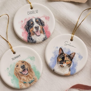May include: Three round white ceramic ornaments with gold hanging strings. Each features a watercolor-style pet portrait: a Bernese Mountain Dog labeled CHARLIE, a Golden Retriever labeled SUNNY, and a calico cat labeled Salem.