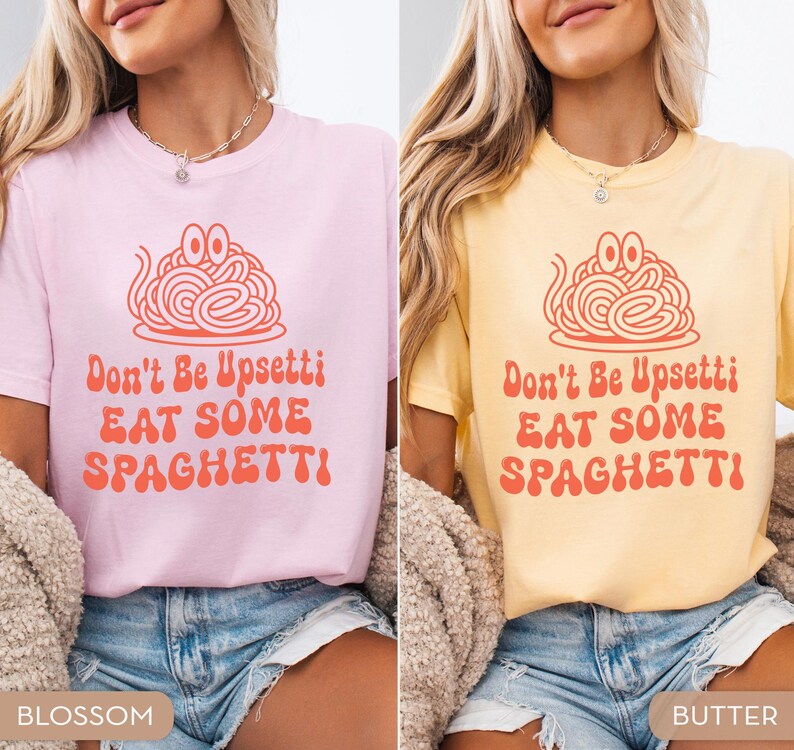 May include: Two t-shirts, one pink and one yellow, each with a spaghetti graphic and the text "Don't Be Upsettti EAT SOME SPAGHETTI!". The shirts are short-sleeved and worn with denim shorts. The pink shirt is labeled "Blossom" and the yellow shirt is labeled "Butter".