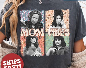 May include: A dark gray t-shirt with a vintage-style graphic featuring four women with the text "MOM VIBES".