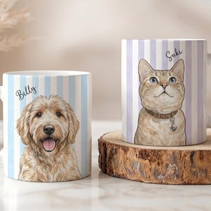 May include: Two white ceramic mugs featuring custom pet illustrations. The left mug displays a golden-colored dog with the name Billy, set against light blue vertical stripes. The right mug shows a tan cat with the name Suki, set against light purple vertical stripes.