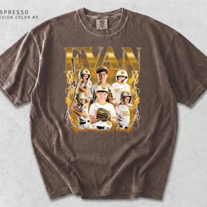 May include: Espresso-colored t-shirt featuring a baseball team photo with the name "EVAN" in gold lettering. The design includes a team photo with lightning bolt accents. The shirt has a crew neck and short sleeves.