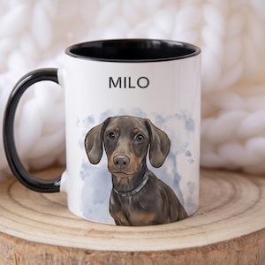 May include: White ceramic mug with a black handle and rim, featuring a watercolor illustration of a dachshund dog. The dog is brown and tan with a silver collar. The name "MILO" is printed above the dog.