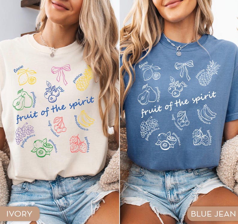May include: Two t-shirts, one ivory and one blue, each featuring a colorful graphic design. The design includes various fruits and the words "fruit of the spirit." The ivory shirt has a multi-colored design, while the blue shirt has a white design.