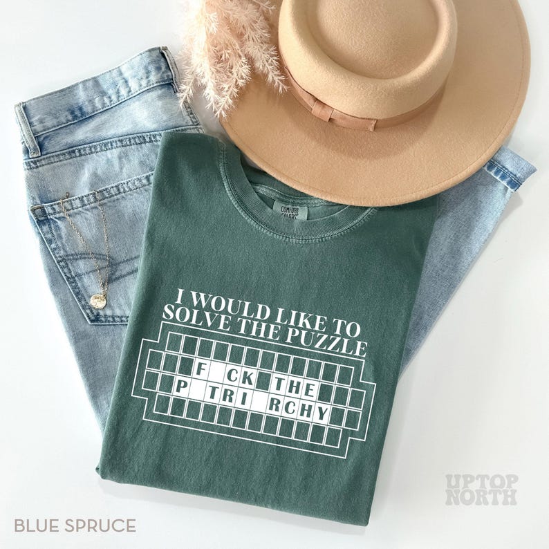 May include: A green t-shirt with the text "I would like to solve the puzzle" and a white scrabble board with the letters "FCK THE PTRI RCHY".