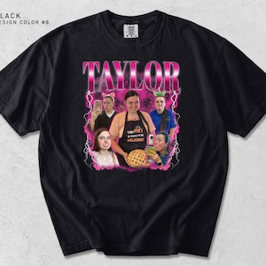 May include: Black t-shirt with a graphic featuring the name "TAYLOR" in pink, outlined in white, above a photo collage. The collage includes images of people, with text that reads "THE SHIT IS GONNA BE DELICIOUS!"