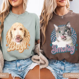 May include: Two t-shirts, one bay-colored and one espresso-colored, each featuring a pet portrait. The bay shirt has a dog portrait with the name "Benji" in retro lettering. The espresso shirt has a cat portrait with the name "Smokey".