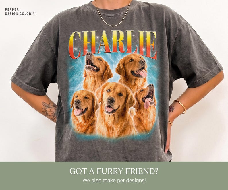 May include: A charcoal gray short-sleeve t-shirt featuring a graphic print of five golden retriever dogs. Above the dogs, the name CHARLIE is printed in a bold, red-to-yellow gradient font. The background of the graphic includes blue lightning.