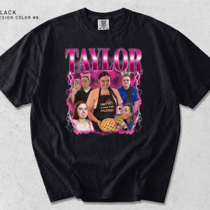 K&ouml;nnte beinhalten: Schwarzes T-Shirt mit einem rosa-wei&szlig;en Grafikdesign des Namens "TAYLOR" &uuml;ber einer Fotocollage. Die Collage enth&auml;lt Bilder von Personen mit dem Text "THE SHIT IS GONNA BE DELICIOUS!" auf einer Sch&uuml;rze.