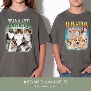 May include: Two charcoal gray t-shirts. The left shirt features five cats and the text TOAST in white letters. The right shirt displays five corgi dogs and the text WINSTON in yellow and red letters. Both shirts have short sleeves and crew necks.