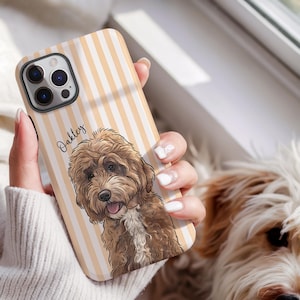 May include: A phone case featuring a light orange and white vertical striped background with a detailed illustration of a brown curly-haired dog. The name Oakley is printed in black script text next to the dog illustration on the phone case.