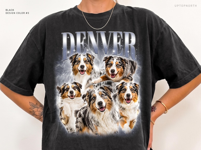 May include: A black short-sleeve t-shirt featuring the word DENVER in large silver metallic-style lettering at the top. Below the text is a graphic collage of five Australian Shepherd dogs with blue merle and brown fur, set against a hazy, glowing background.