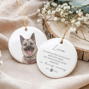 May include: Two round white ceramic ornaments with gold hanging strings. One features a colorful illustration of a tan and grey dog with a pink tongue. The other displays the text Luna, a memorial poem, a paw print, and the years 2013 and 2026.