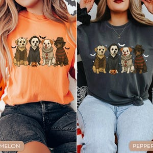 May include: Two t-shirts, one melon and one pepper, each featuring a graphic of four dogs dressed as horror movie characters. The dogs are sitting in a row with a small pumpkin in front of them, with bats in the background.