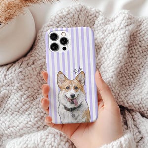 May include: A phone case with a vertical striped pattern in white and lavender. The case features a portrait of a Corgi dog with the name "Rick" written above the dog. The dog is wearing a collar with a tag.