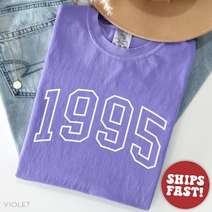 Puede incluir: Una camiseta morada con el a&ntilde;o 1995 impreso en blanco en la parte delantera. La camiseta est&aacute; hecha de un material suave y c&oacute;modo, ideal para el uso diario.
