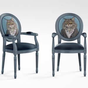 May include: Two blue upholstered chairs with oval backs featuring a portrait of a cat wearing a suit and tie. The chairs have a classic design with fluted legs.