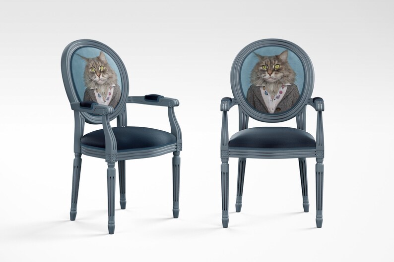 May include: Two blue upholstered chairs with oval backs featuring a portrait of a cat wearing a suit and tie. The chairs have a classic design with fluted legs.
