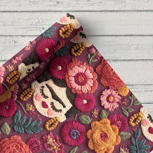 Op de afbeelding: Close-up van een opgerolde stof met een geborduurd bloemenontwerp. Het ontwerp heeft een herhalend patroon van kleurrijke bloemen, bladeren en gestileerde gezichten op een dieppaarse achtergrond. Het borduurwerk gebruikt tinten roze, oranje en groen.