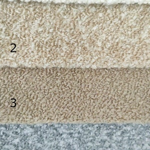 K&ouml;nnte beinhalten: Nahaufnahme von f&uuml;nf strukturierten Stoffmustern in verschiedenen Farben. Das oberste Muster ist cremefarben, gefolgt von Beige, Hellbraun, Grau-Blau und Altrosa. Die Stoffe haben eine geschlungene Boucl&eacute;-Textur, geeignet f&uuml;r Polster oder Dekorationszwecke.