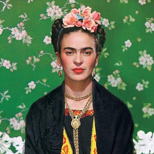 May include: Portrait of a woman with dark hair, wearing a floral crown, gold jewelry, and a black shawl. The background is a green floral pattern. The woman has a serious expression and red lipstick.
