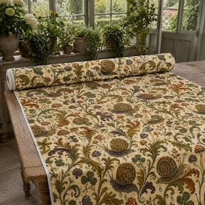 May include: A roll of fabric featuring a repeating pattern of snails, mushrooms, and leafy foliage in shades of olive green, brown, and cream. The textile displays a dense botanical design with swirling vines and clover motifs across the surface.