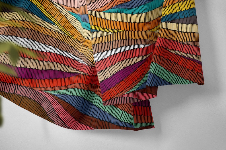 May include: A colorful fabric with a repeating pattern of horizontal stripes made of small, hand-drawn lines. The fabric is folded and draped over a white surface.
