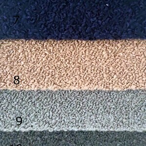 K&ouml;nnte beinhalten: Nahaufnahme von Stoffmustern in verschiedenen Farben. Die Farben umfassen Rot, Marineblau, Beige, Grau, Dunkelgrau und Schwarz. Der Stoff hat ein strukturiertes, geschlungenes Aussehen.