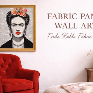 Può includere: Un'opera d'arte murale su pannello di tessuto incorniciato con un ritratto in bianco e nero di Frida Kahlo con rossetto rosso e un copricapo floreale. L'opera è esposta sopra una poltrona rossa. Il testo sulla parete recita "FABRIC PANEL WALL ART Frida Kahlo Fabric Panel."
