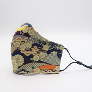 May include: A face mask with a colorful Japanese-inspired pattern featuring flowers, waves, and geometric designs. The mask is made of fabric and has black elastic ear loops.