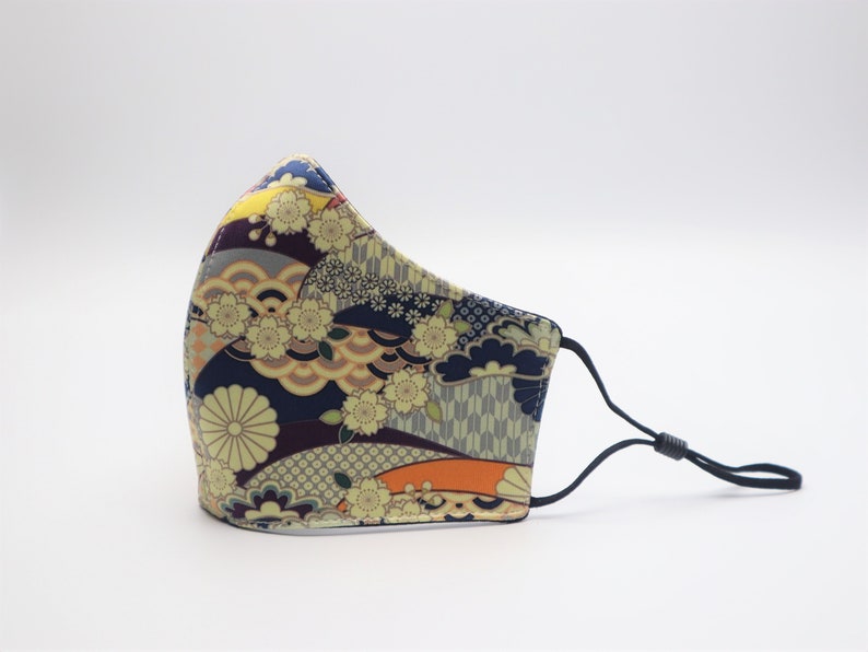 May include: A face mask with a colorful Japanese-inspired pattern featuring flowers, waves, and geometric designs. The mask is made of fabric and has black elastic ear loops.