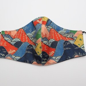 May include: A reusable face mask with a colorful Japanese-inspired mountain and wave pattern. The mask is made of fabric and has adjustable ear loops.