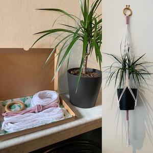 May include: A kit for making a macrame plant hanger. The kit includes white and pink cord, a wooden ring, and instructions. The kit is shown next to a potted plant.