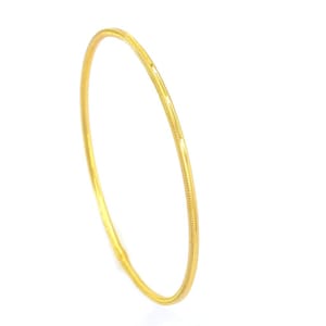 Puede incluir: Un brazalete de oro simple con un acabado liso y pulido.