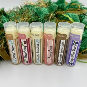 May include: Six different flavored lip balms in tubes with festive holiday-themed labels. The flavors are Creme Brulee, Black Cherry, Vanilla Snowdrop, Candy Cane, S'mores Smooches, and Sugar Plum Punch.