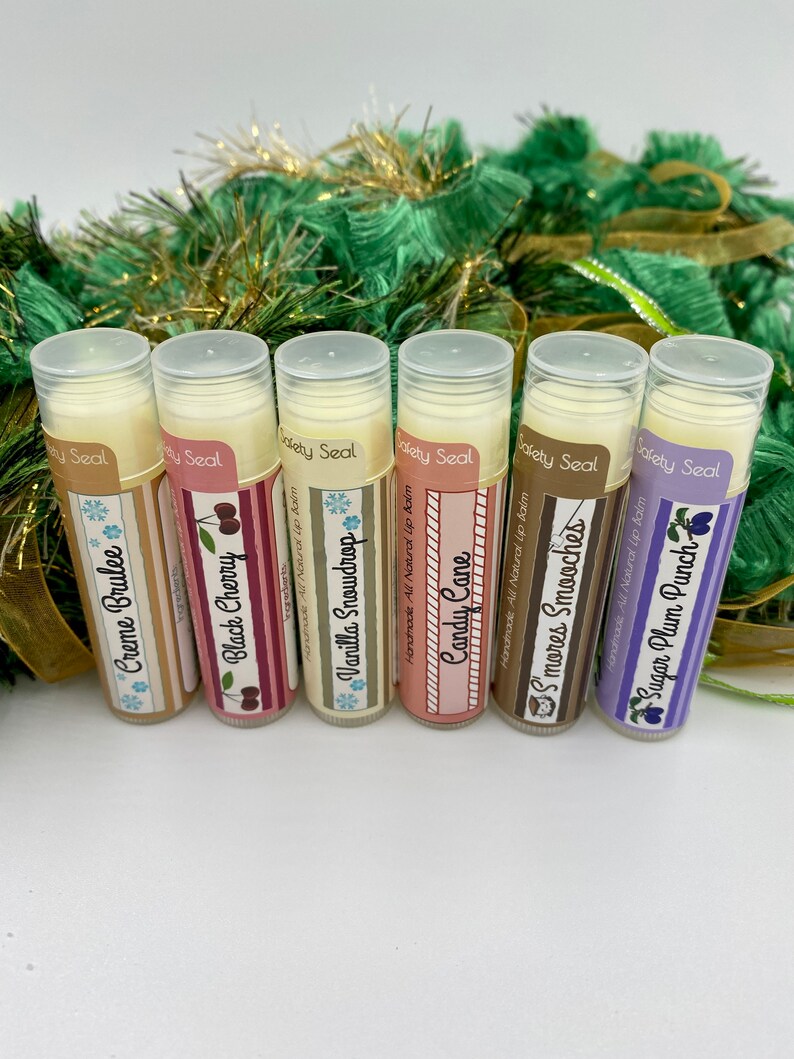 May include: Six different flavored lip balms in tubes with festive holiday-themed labels. The flavors are Creme Brulee, Black Cherry, Vanilla Snowdrop, Candy Cane, S'mores Smooches, and Sugar Plum Punch.