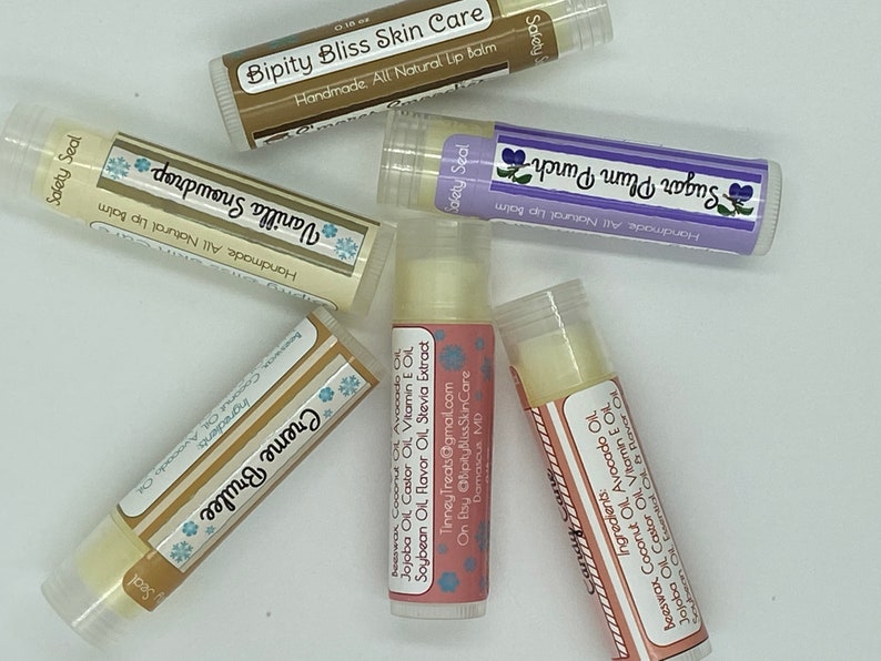 May include: Six different flavored lip balms in clear tubes with colorful labels. The labels have snowflakes and text that reads "Safety Seal", "Handmade All Natural Lip Balm", "Vanilla Snowdrop", "Creme Brulee", "Sugar Plum Punch", and "Bipity Bliss Skin Care".