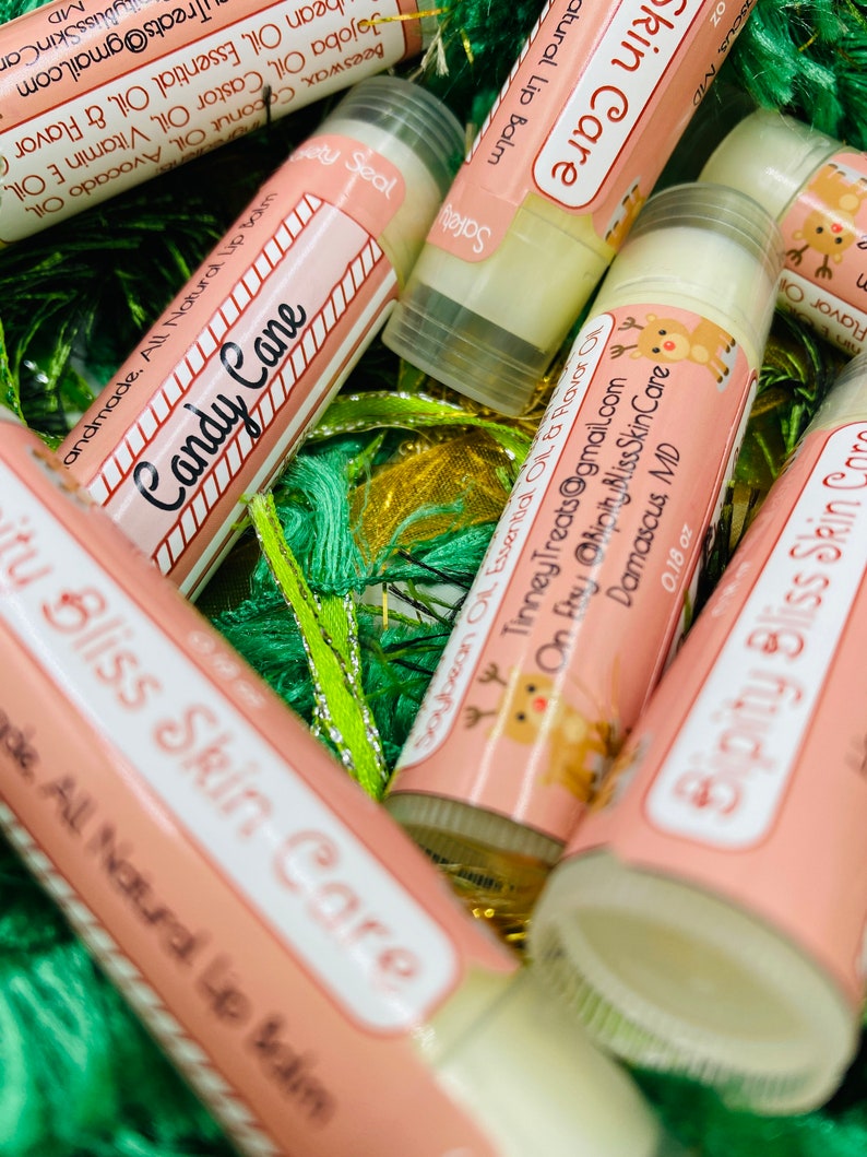 May include: A collection of pink and white lip balm tubes with a reindeer design and the text "Ripity Bliss Skin Care". The lip balms are labeled with different flavors, including "Candy Cane" and "Soybean Oil Essential Oil & Flavor Oil".
