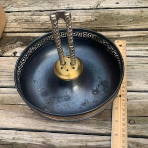 May include: A black metal nutcracker with a gold base and a decorative border. The nutcracker has a handle with a silver finish.