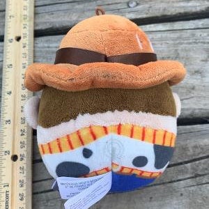 May include: A plush toy of Woody from the Toy Story franchise. Woody is wearing his signature cowboy hat and vest. He has a brown vest with yellow and red stripes and a white star on the front. The toy is made of soft, plush fabric.