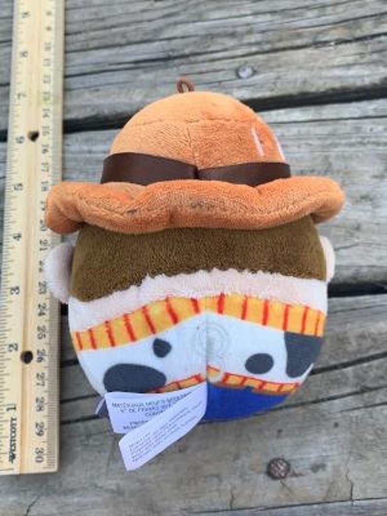 May include: A plush toy of Woody from the Toy Story franchise. Woody is wearing his signature cowboy hat and vest. He has a brown vest with yellow and red stripes and a white star on the front. The toy is made of soft, plush fabric.