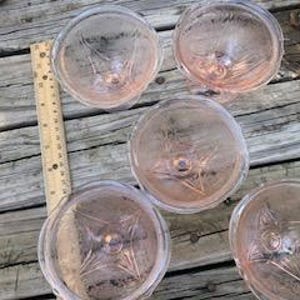 May include: Set of five pink glass dessert dishes with a delicate etched design. The dishes have a footed base and are perfect for serving ice cream, pudding, or other desserts.