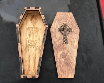 May include: Two wooden boxes shaped like coffins. One box has a skeleton inside and the other has a Celtic cross.
